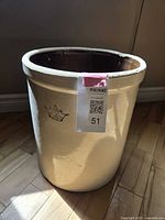 Full view of tall two-tone ceramic crock with cream exterior and darker interior. Shows planting or storage crock shape.