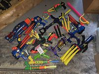 Overview of large lot containing multiple Nerf and assorted toy blasters with orange and yellow foam darts