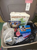 Top view of tote bin showing various insect-related items including teaching pictures box, book, plastic containers and gadgets.
