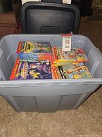Large gray plastic tote filled with stacks of Magic School Bus chapter books, some bundled with rubber bands.