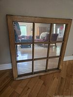Full view of large window pane mirror showing wooden frame and nine segmented glass panels reflecting room interior.