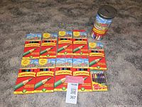 Group photo showing ten unopened boxes of Laurentien colored pencils, one box of 24 crayons, and the vintage tin on carpeted floor including a Masold tag.