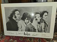 Full view of the plaqued poster showing The Beatles in black and white with signatures and logo.