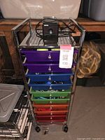 Front view of rainbow coloured rolling cart with eight drawers and Boston electric pencil sharpener on top.