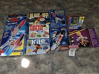 Full view of the lot including rocket kits, paper airplane and kite craft kits, aquatic garden kit, and a robotic constructible toy kit.