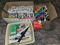Photo of boxes containing Crayola broad line markers, Trend porous pens, Scotch tapes and various school supplies in packaging.