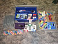 Overview photo showing the entire lot with blue caddy, multiple marker boxes, paper clips, cassette tape, and other items