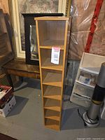 Photo showing narrow 6-compartment wooden cube shelf standing upright next to furniture and storage bins.