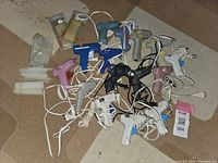 Top view of 15 assorted electric glue guns mixed on floor with glue sticks on side