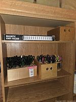 Image showing wooden shelving with three caddies filled with scissors and a boxed magnetic knife holder on top shelf.