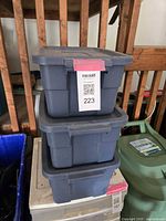 Three small dark grey Rubbermaid plastic tote bins stacked with lids on top.