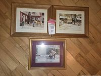 Three framed Trisha Romance prints, two with wooden frames and white mats, one with gold frame and purple mat, arranged on parquet floor.