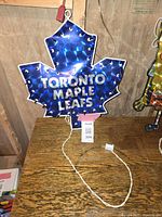 Front view of the Toronto Maple Leafs maple leaf light-up decoration plugged in and lit up showing the text and embedded small lights.
