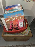 Two boxes filled with dinosaur-themed books showing multiple titles and colorful covers