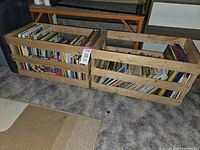 Two wooden crates side by side filled with assorted children's books visible through crates' slats.