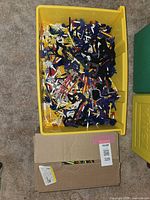Yellow plastic drawer filled with assorted KNEX parts showing rods and connectors in multiple colors
