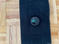 Close-up of circular digital control panel showing illuminated display and buttons on black fabric belt.