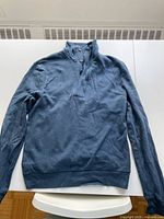 Front view of blue quarter-zip sweatshirt laid flat showing overall condition and style