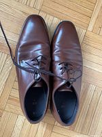Top view of two brown leather dress shoes with laces, showing smooth surface and slight creasing on the leather upper.