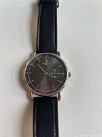 Close-up of the watch face showing dark dial, silver hands, hour markers, and subdial.