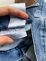 Close-up photo showing the inner label of the jeans indicating size W 28 L 32.