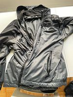 Full view of the men's two-toned Swiss Tech jacket showing black and grey weather-resistant outer material with zippered pockets and collar area.