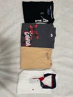 Four men’s shirts neatly folded on white surface, showing each shirt’s front and color distinctly