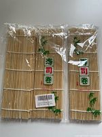 Two sushi mats sealed in plastic packaging with green and red Japanese characters on the label, bamboo illustrations on the mat.