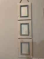 Front view of the triple hanging picture frames showing the distressed white wood and grey inner frame border.