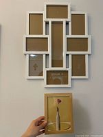 White multi-photo collage frame hung on wall showing six rectangular photo slots around a tall central slot.