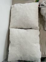 Two white square fluffy pillows stacked, showing plush texture