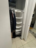 White fabric hanging closet organizer installed in a closet with hanging coats nearby, showing full length and shelf spacing.