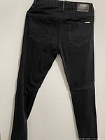 Back view of black pants showing two rear pockets and Zara brand leather patch on waistband.