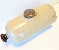 Full view of stoneware foot warmer showing metal screw cap and brown glazed neck