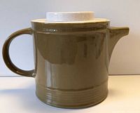 Side view of olive-green stoneware teapot, handle and spout visible