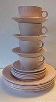 Stack of cups on saucers atop plates, shows colour and quantity