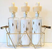 Front view of three patterned glass dispensers in gold wire caddy