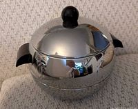 Front view of chrome ice bucket with lid showing penguin embossing and Bakelite knob