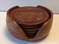 Stack of carved wooden coasters inside carved holder