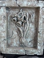 Front view of the bas-relief plaque depicting daffodils with visible cracks and aged patina.