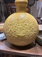 Front view showing the intricate floral embossing on the copper vessel with a chalice design in the center.