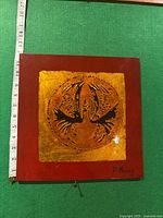 Front view of the square mixed media artwork showing red base, gold textured square, circular relief abstract figure, and signature.
