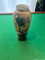 Front view of tall porcelain vase with hand-painted naturalistic tree scenery and scalloped rim.