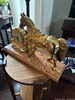 Side view of the vintage mantel clock showing brass horse figurine and wood base