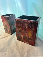 Pair of rectangular vases with abstract red-black glaze and yellow highlights, photographed on neutral draped fabric background
