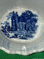 Close-up of base interior showing detailed blue transferware scenic design with buildings and trees on white ironstone ceramic with scalloped edge rim.