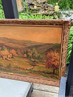 Close-up angled view of left side showing detailed frame carving and painting texture of autumn trees and landscape.