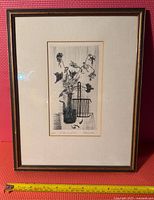 Framed artwork with a print titled 'Le Bouquet Sec' featuring a black line etching of a vase and flowers, signed and numbered 12/50 by Amsler.