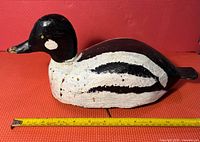 Photo showing side view of carved wooden duck decoy with measuring tape indicating length roughly 14 inches.
