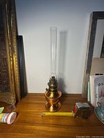 Full view of vintage copper lantern with glass chimney on wood surface, showing size with measuring tape